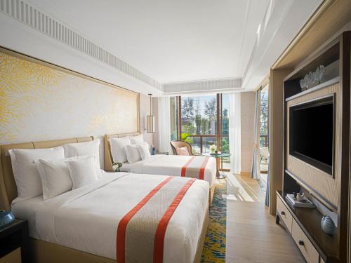 a hotel room with two beds and a flat screen tv at InterContinental Phuket Resort, an IHG Hotel in Kamala Beach