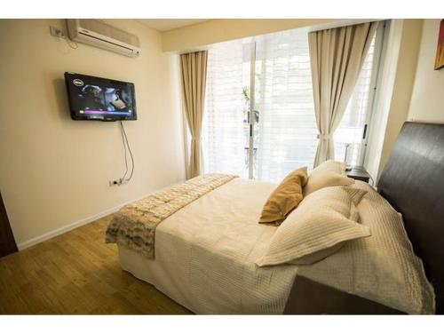 Casa ivana 1 في بوينس آيرس: غرفة نوم مع سرير وتلفزيون على الحائط
