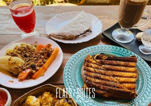 una mesa de madera cubierta con platos de comida y bebida en NOVIDADE FLATS COMFORT na Vila de São Jorge - Chapada dos Veadeiros en Sao Jorge