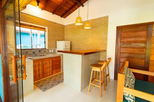 a kitchen with a sink and a counter with chairs at Vila Marina in Arraial d'Ajuda