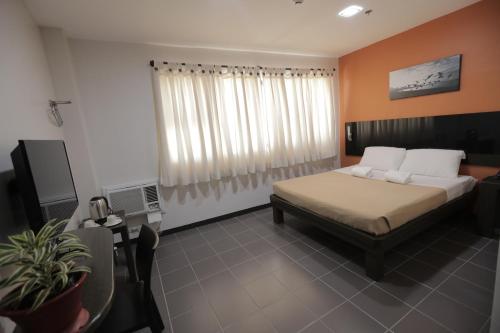 ein Schlafzimmer mit einem Bett und einem TV in der Unterkunft Ialodge in Ormoc City
