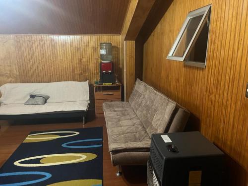 um pequeno quarto com uma cama e um sofá em Cabaña Quillaipe orilla del mar em Puerto Montt