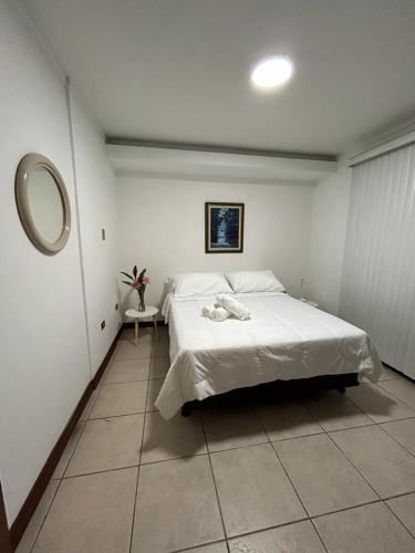 Schlafzimmer mit einem weißen Bett und einem Spiegel in der Unterkunft Casa Calas in Alajuela