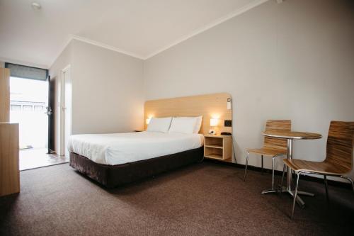 a hotel room with a bed and a table and chairs at Colonial Motel Richmond in Richmond