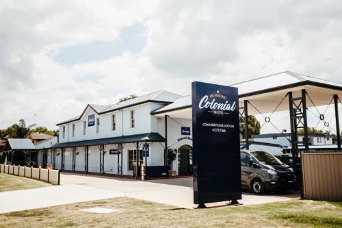 a sign in front of a building with a car dealership at Colonial Motel Richmond in Richmond