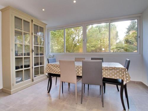 une salle à manger avec une table, des chaises et des fenêtres dans l'établissement Appartement T3 à Balaruc-les-Bains – 2 Chambres, Clim, WiFi, Parking, Proche Thermes, Classé 4* - FR-1-553-189, à Balaruc-les-Bains