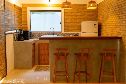 a kitchen with three bar stools and a counter at Vila Marina in Arraial d'Ajuda