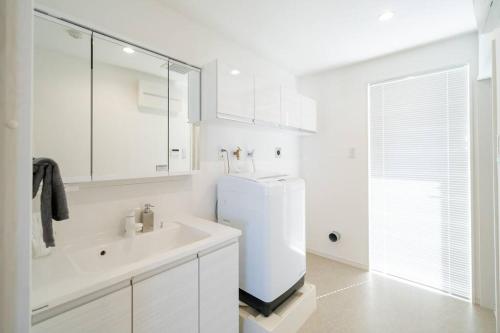 a white bathroom with a sink and a refrigerator at The Penthouse Ginowan in Makiminato