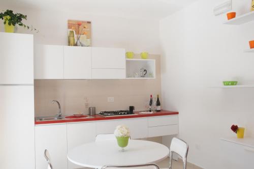 a white kitchen with a table and a sink at Settessenze Residence & Rooms in Agropoli