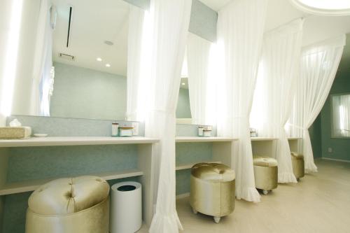 a bathroom with white curtains and stools and a mirror at Shohakuen Hotel in Kitakyushu