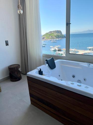 a bathroom with a large tub with a large window at Liman Hotel Gümüslük - Adult Only in Bodrum City