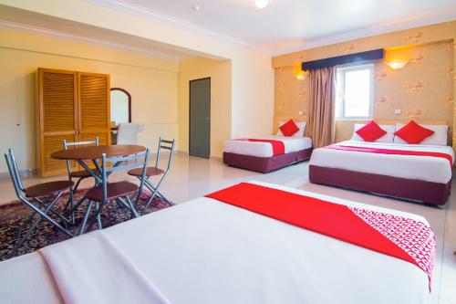 a hotel room with two beds and a table at OYO 528 Andaman Sea Hotel in Batu Ferringhi
