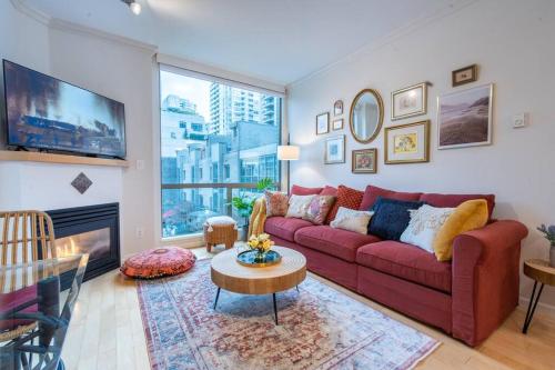 a living room with a red couch and a large window at Heart of Downtown King Suite/Parkng/Pool/Gym/Sauna in Vancouver