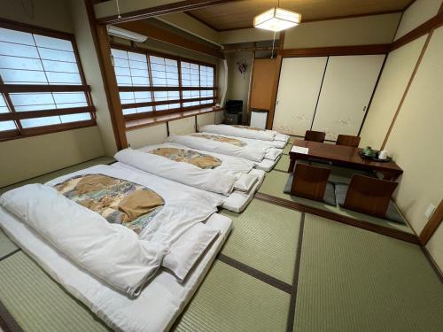 a row of beds in a room with windows at Ryokan Kosen Kazeya Group in Nara