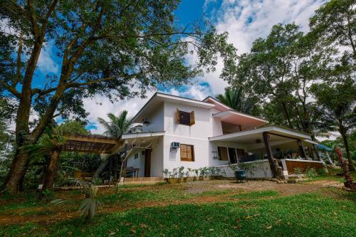 una casa bianca con degli alberi di fronte di Almost Heaven Lake Resort by Cocotel a Cavinti
