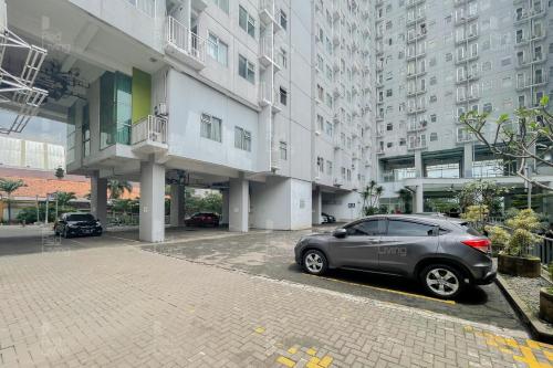 a car parked in front of a large building at RedLiving Apartemen Easton Park Jatinangor - Rajes Room in Sumedang