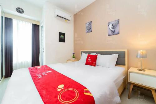 - une chambre avec un lit et une couverture rouge dans l'établissement RedLiving Apartemen Grand Kamala Lagoon - Icha Rooms Tower Barclay South with Netflix, à Bekasi
