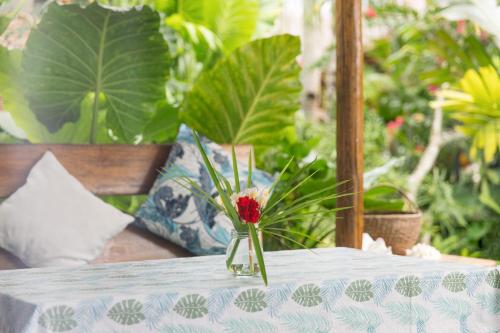 a vase with a red flower sitting on a table at Hygge Siargao in General Luna