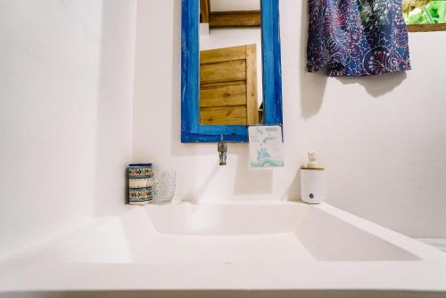 a bathroom with a white sink and a blue mirror at Hygge Siargao in General Luna