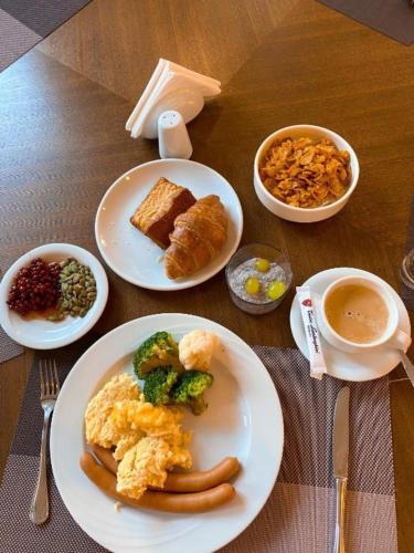 バトゥミにあるBatumi Luxury Resort & Sea View Aparthotelの朝食の食べ物の皿とコーヒーカップが置かれたテーブル