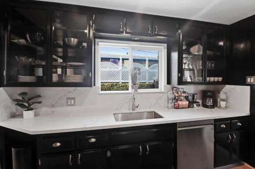 a kitchen with black cabinets and a sink and a window at Luxury Home - 7mins LAX/Beach, 405/SoFi nearby in Hawthorne