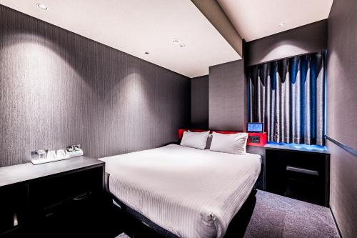 a small room with a bed and a desk at Wyndham Garden Sapporo Odori in Sapporo