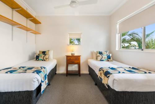 two twin beds in a room with a window at Raffles Mooloolaba in Mooloolaba