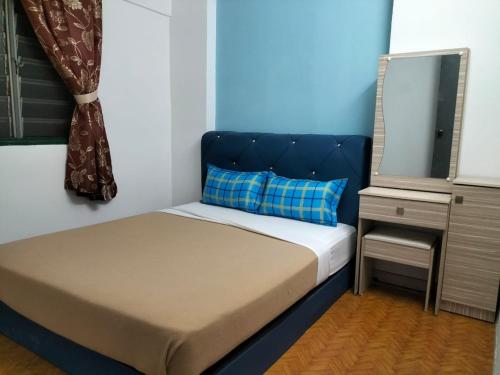 małe łóżko z niebieskim zagłówkiem w pokoju w obiekcie KHAIRUL HOMESTAY PANGSAPURI SUTERA SEBERANG JAYA w mieście Kampong Telok