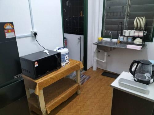 a kitchen with a microwave on a table next to a refrigerator at KHAIRUL HOMESTAY PANGSAPURI SUTERA SEBERANG JAYA in Kampong Telok