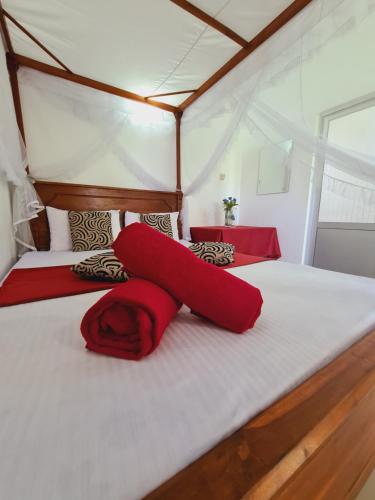 - une chambre avec un grand lit et des draps rouges dans l'établissement Peacock Villa Resort, à Uda Walawe