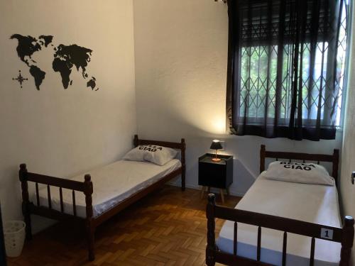 two beds in a room with a world sticker on the wall at Bella Ciao Hostel in Rio de Janeiro