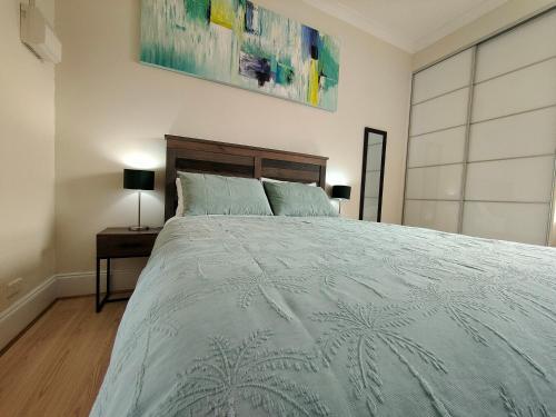 a bedroom with a large bed with a blue comforter at Smugglers Inn Studio Apartments in Victor Harbor