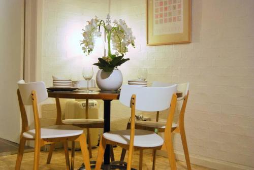 a dining room table with chairs and a vase with flowers at Bimbimbie House Batemans Bay in Surf Beach