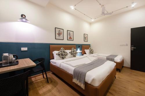 two beds in a room with a table and a tableablish at Convastay Prestige- Near Apollo Hospital & US Consulate in Chennai