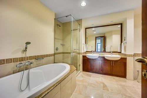 a bathroom with two sinks and a tub and a mirror at South & North Residence Palm Jumeirah in Dubai
