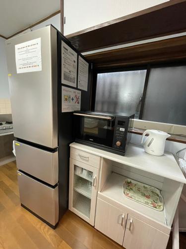 a kitchen with a microwave and a refrigerator at Hana Azusa in Yufuin