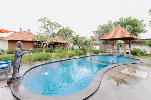 a pool with a statue spraying water from a fountain at The Lavana Jhonny Kibung Villas Lembongan in Nusa Lembongan