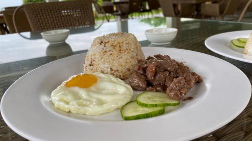 a plate of food with meat and egg on a table at El Pueblo De Hermano by Cocotel in Lian