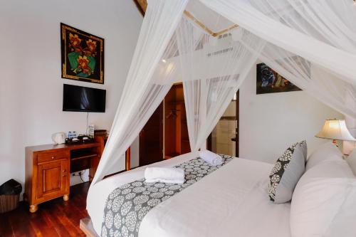 a bedroom with a white bed and a desk at The Lavana Jhonny Kibung Villas Lembongan in Nusa Lembongan