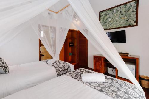 a bedroom with two beds and a tv at The Lavana Jhonny Kibung Villas Lembongan in Nusa Lembongan