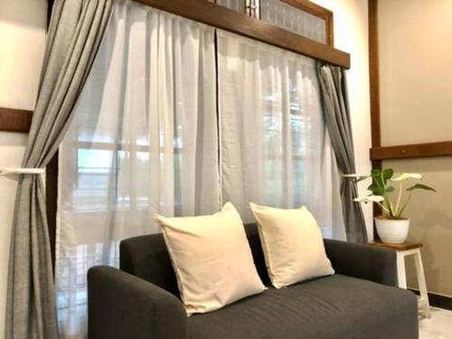 a couch with two pillows in front of a window at Citrus-House com Hotel in Bogor