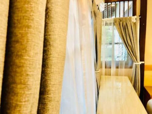 a room with a window with curtains and a table at Citrus-House com Hotel in Bogor