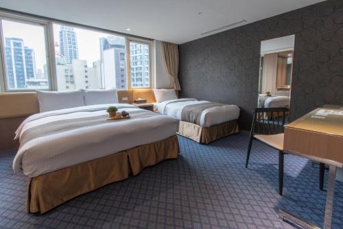 Habitación de hotel con 2 camas y escritorio en Muzik Hotel - Ximen Station Branch, en Taipéi