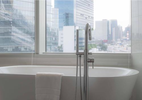 a bath tub in a bathroom with a large window at Modena by Fraser Bangkok in Bangkok