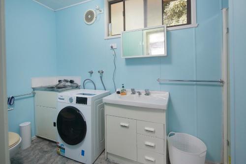 uma casa de banho azul com uma máquina de lavar roupa e um lavatório em Melbourne Guest house em Doveton