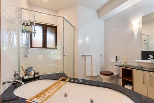 een badkamer met een bad, een wastafel en een toilet bij The Savannah Villa in Port Douglas