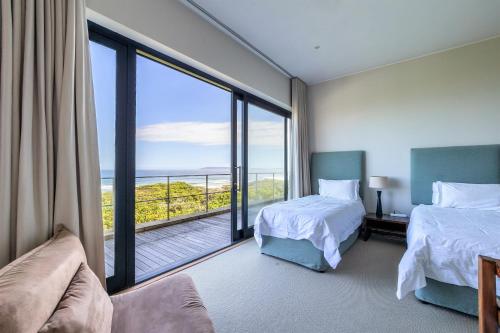 a hotel room with two beds and a large window at Whaleshaven 14 in Plettenberg Bay