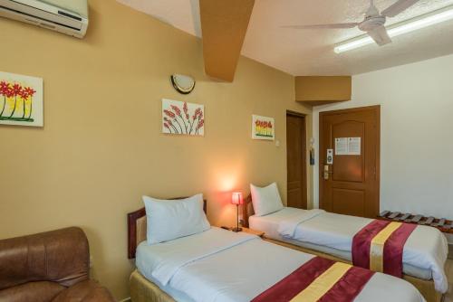 a hotel room with two beds and a chair at Hotel Raha Tower in Dar es Salaam
