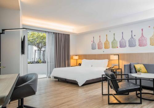 Habitación de hotel con cama, mesa y sillas en Modena by Fraser Bangkok, en Bangkok