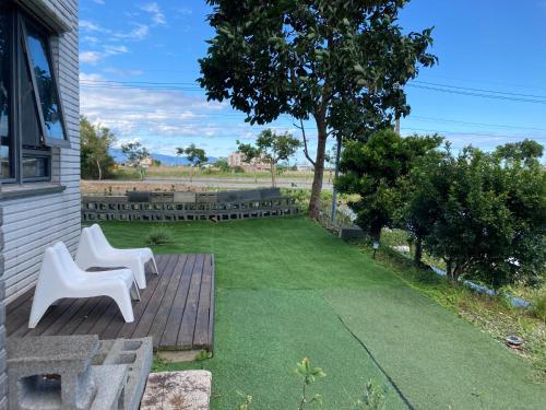 a patio with two white chairs and a lawn at 沐光森野旅宿 永續旅遊 in Wujie